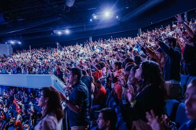 A diverse congregation of Christian believers raising their hands in worship at a discipleship gathering, representing the Great Commission mission to make disciples of all nations